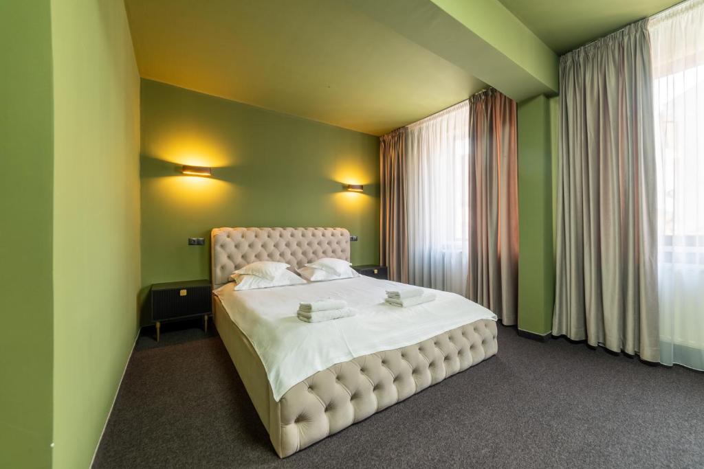 a bedroom with a large bed with green walls at Fullton Central in Cluj-Napoca