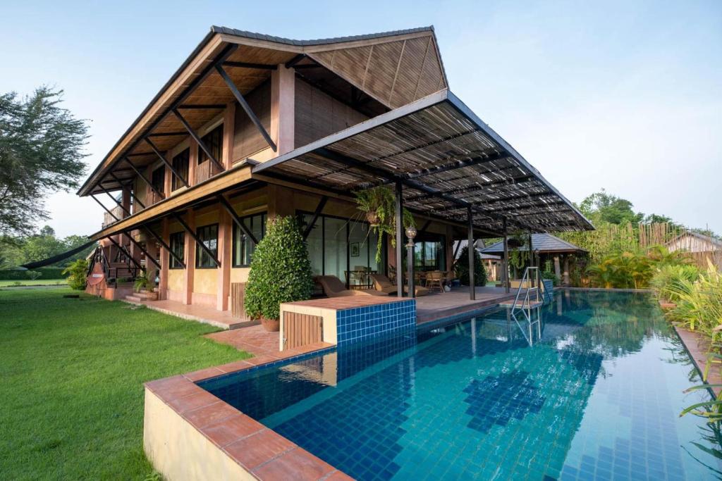 a house with a swimming pool in front of it at Chalala Tropical Villa with 18m Natural Swimming Pool in Chiang Mai