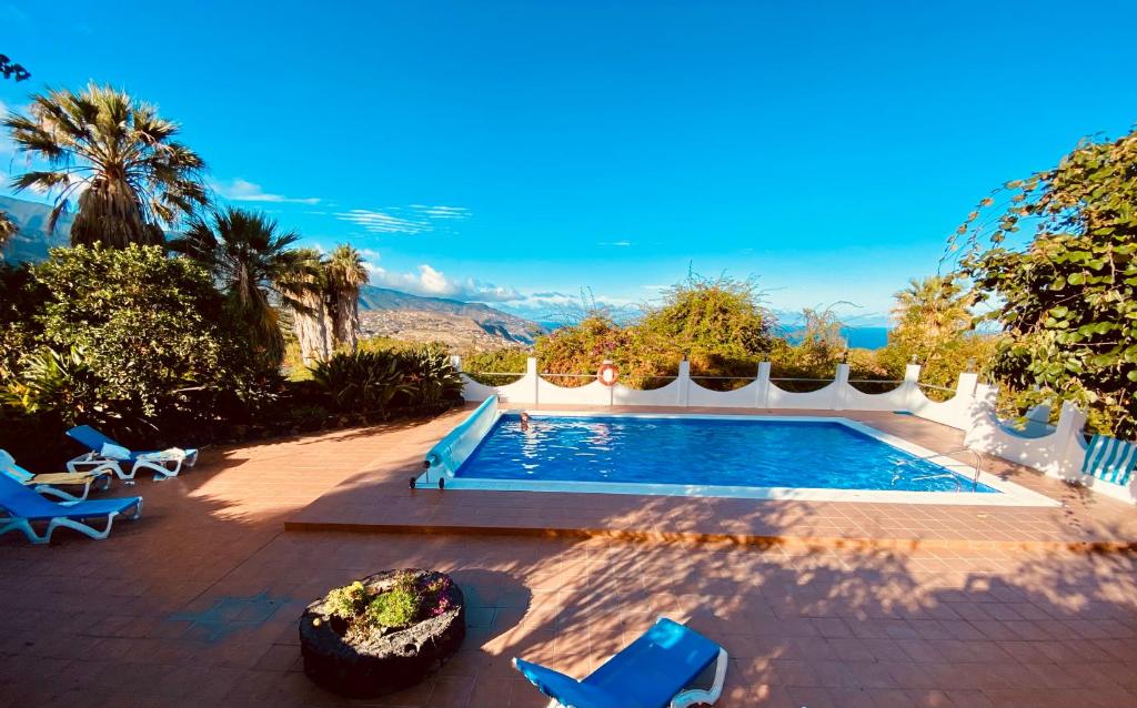 una piscina con sedie blu in un cortile di Spacious characterful villa with spectacular views in quiet rural setting. a Breña Alta