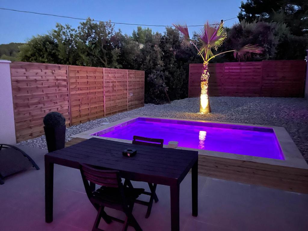 a patio with a table and a purple pool at La Paillote Exotique Spa in Beaucaire