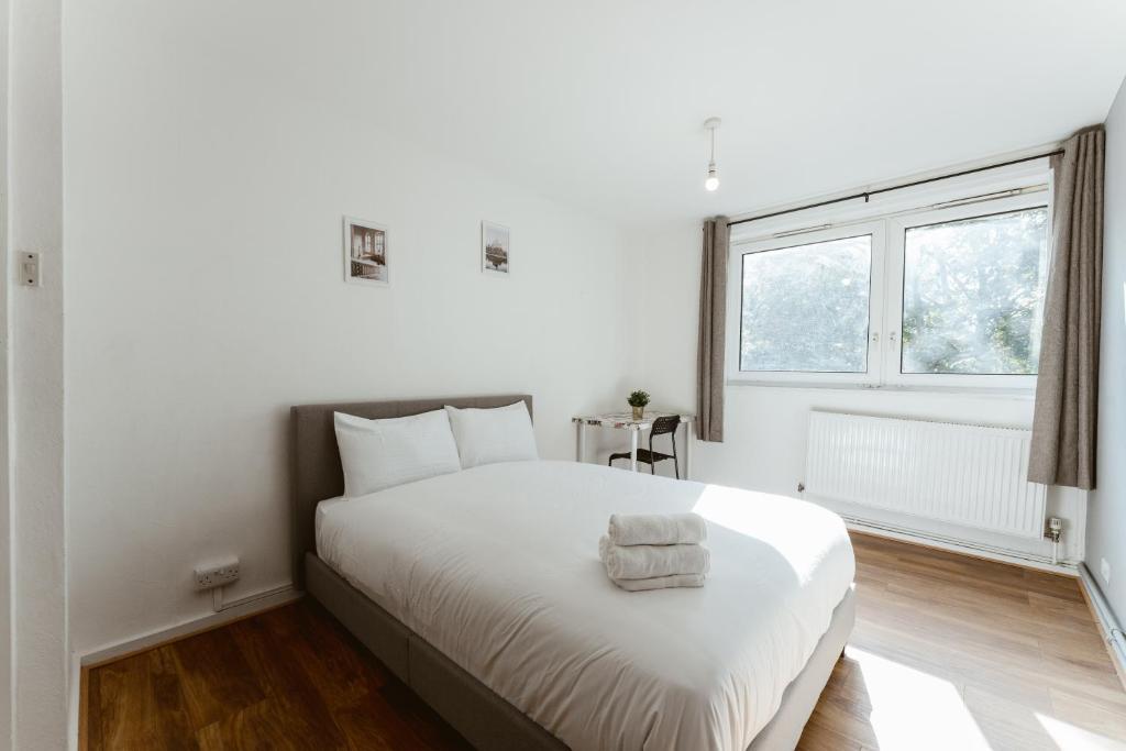 a white bedroom with a large white bed and a window at Shadwell Double Room - 13 in London