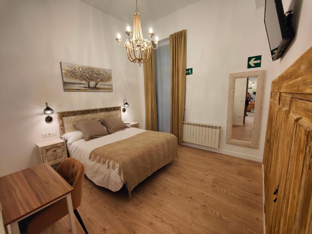 a bedroom with a bed and a table and a chandelier at Apartamentos Santander 1 in Santander