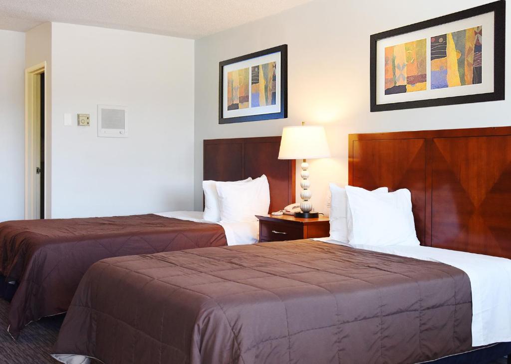 una camera d'albergo con due letti e una lampada di GREELEY UNIVERSITY INN/ GREELEY INN a Greeley