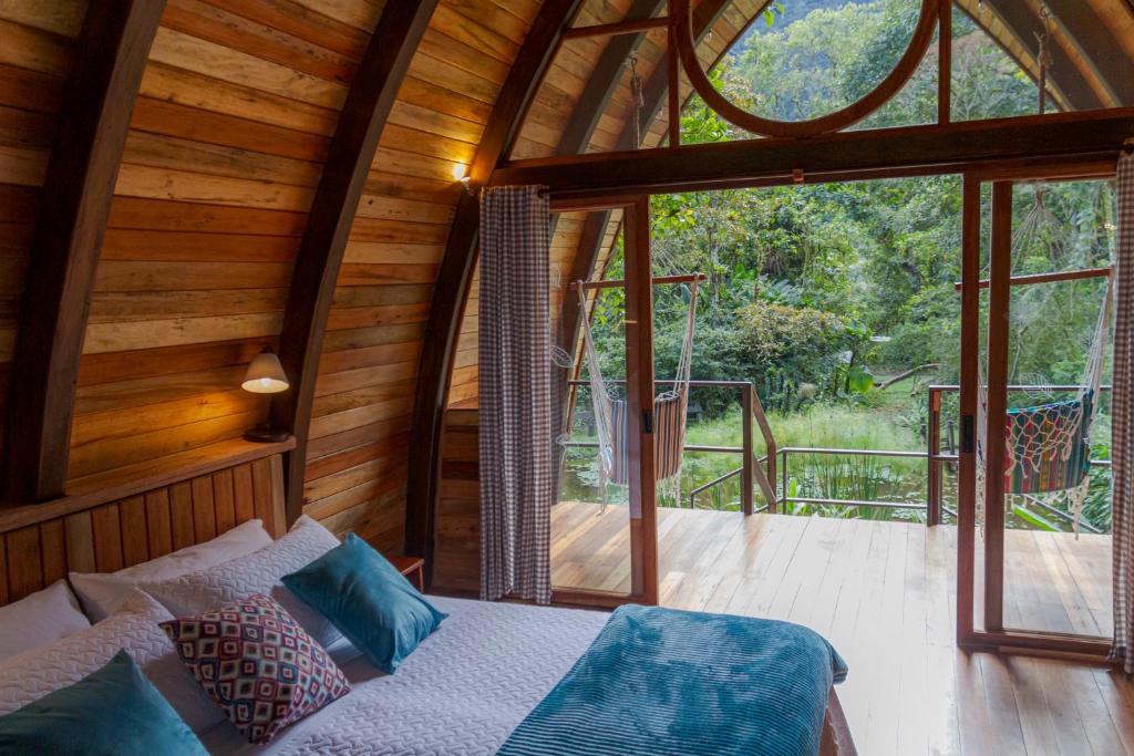 a bedroom in a wooden cabin with a bed and a balcony at Sacha Urco Lodge y Bosque Protector in Mindo