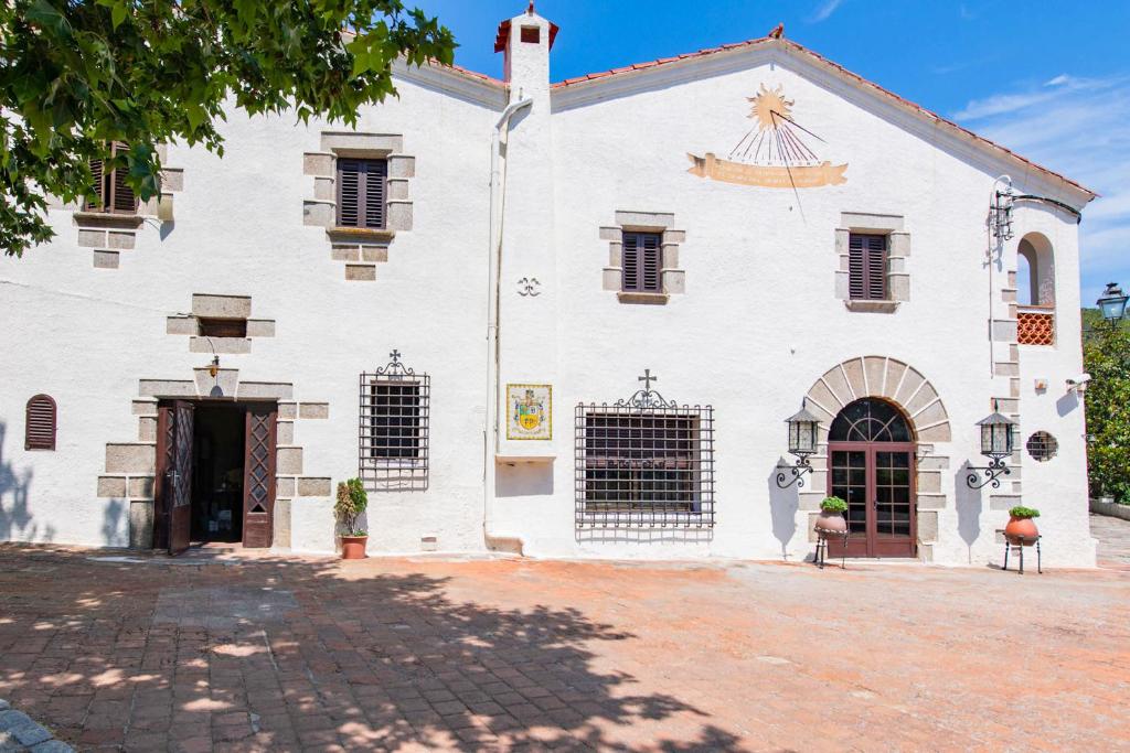 a large white building with a gate and a courtyard at NEW Can Blanch 16th Century Masía Pool Chapel in Argentona