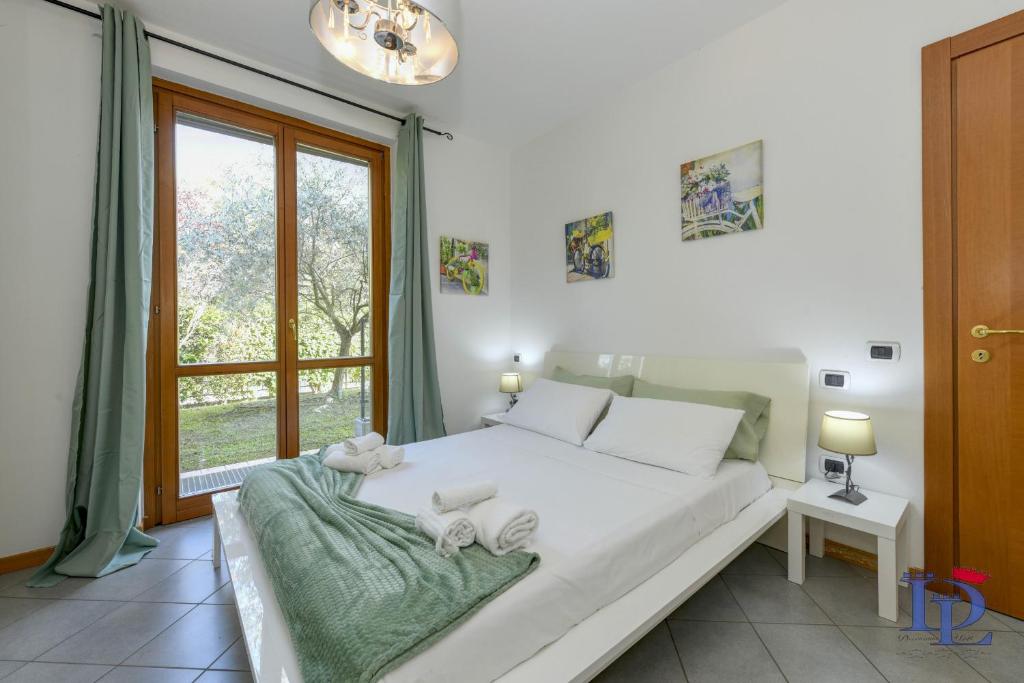 ein weißes Bett in einem Zimmer mit Fenster in der Unterkunft Desenzanoloft Oasis in Desenzano del Garda