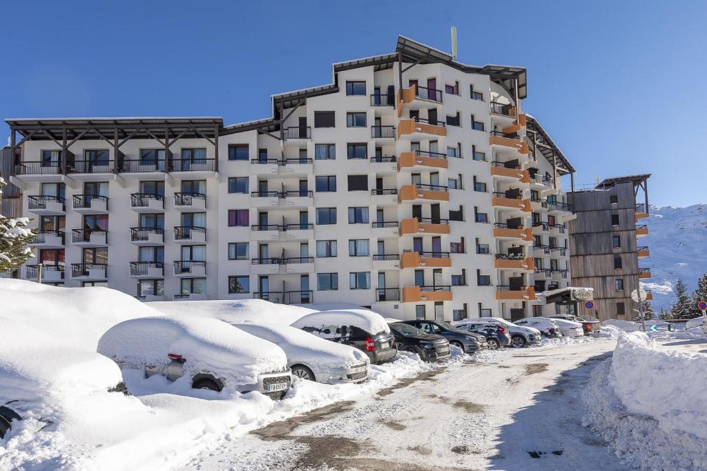 レ・メニュアールにあるRésidence Le Médian - Les Ménuiresの大きな建物の隣にある雪に覆われた駐車場