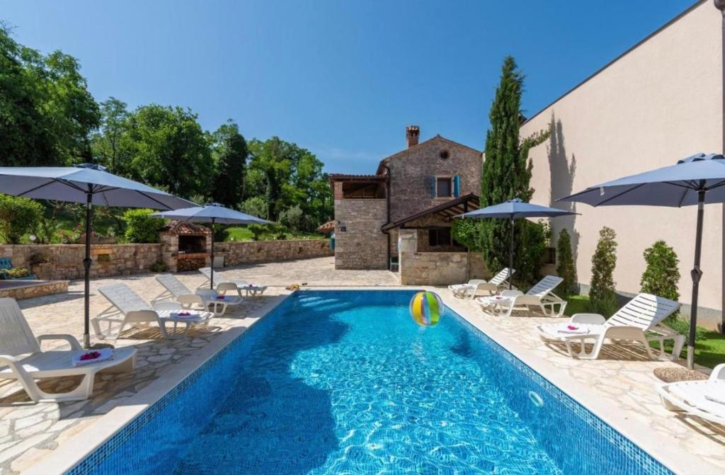 a swimming pool with chairs and umbrellas at Holiday Houses Luan in Poreč
