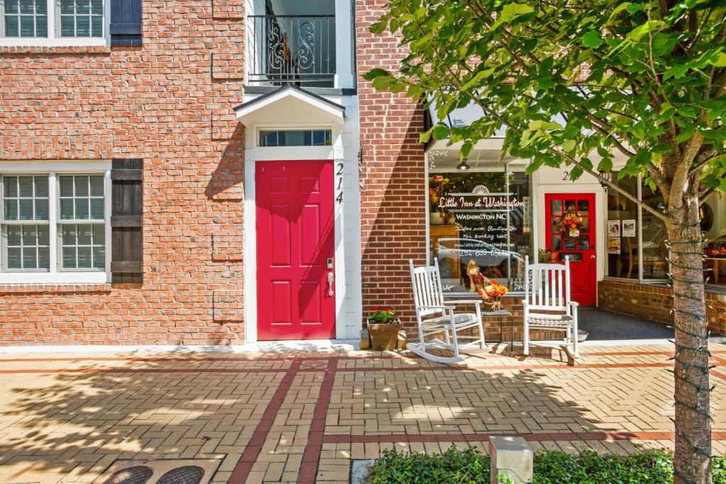 a red door on a brick building with chairs outside at Little Inn on Main in Washington