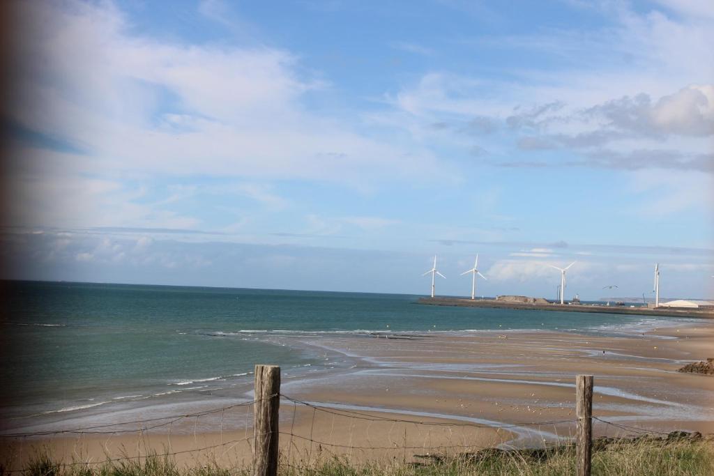 een strand met windmolens in het water en een hek bij Mer et Soleil a la cote d'opale in Le Portel