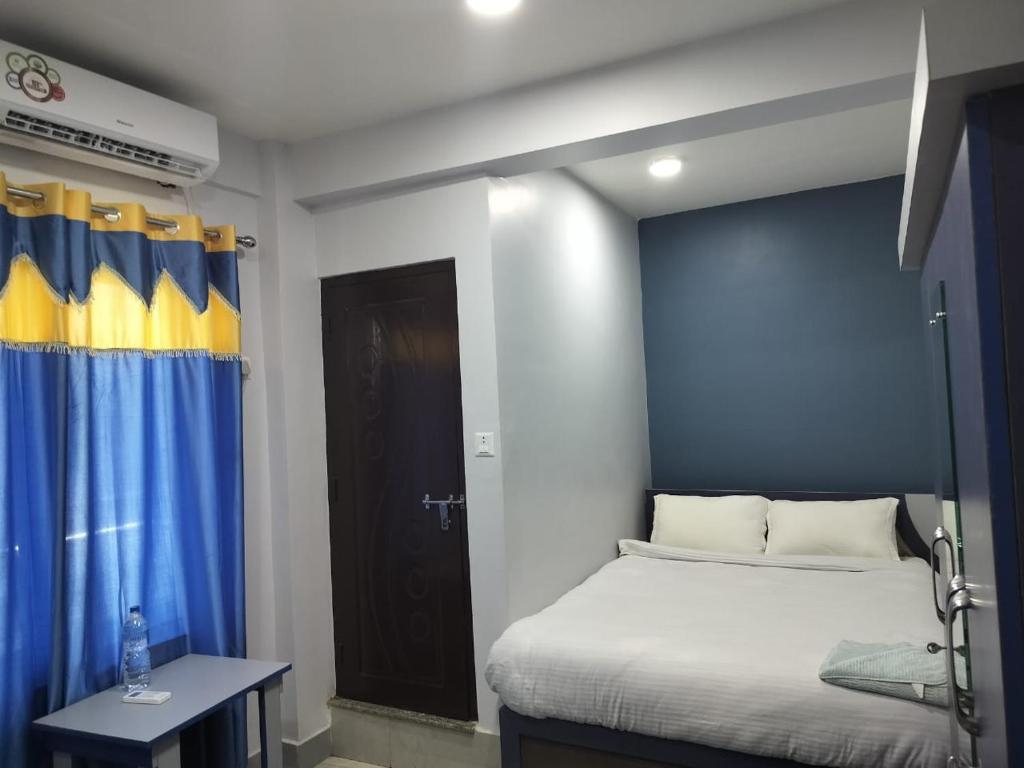 a bedroom with a bed and a blue and yellow curtain at Hotel Homestay Inn in Thimi
