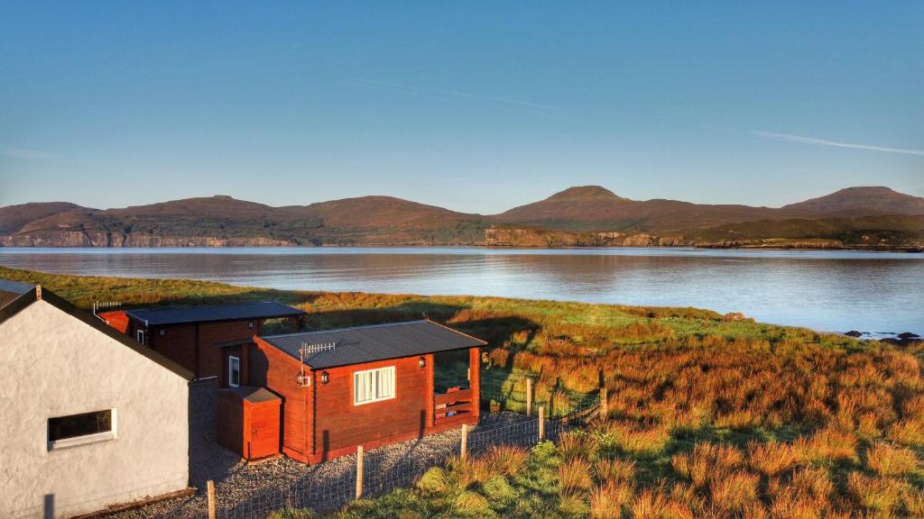 a small house on the shore of a lake at Harlosh Log Cabins in Dunvegan