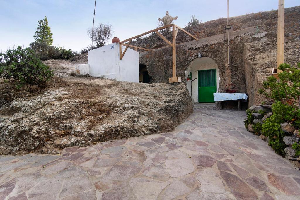 un edificio de piedra con una puerta verde en una colina en La Cuevita de Hilario en Artenara