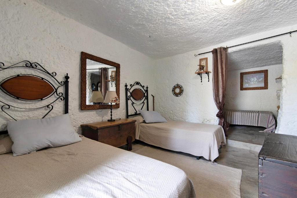 um quarto com 2 camas e um espelho em La Cuevita de Hilario em Artenara