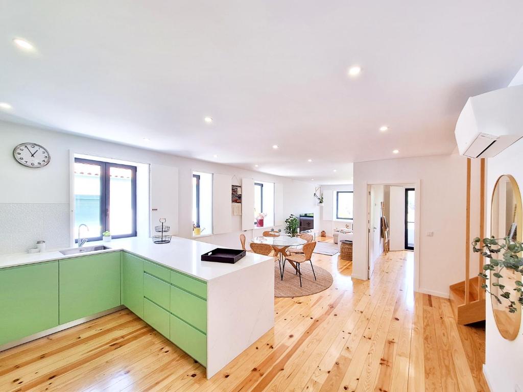 a kitchen with white and green cabinets and a dining room at Tílias House in Covilhã