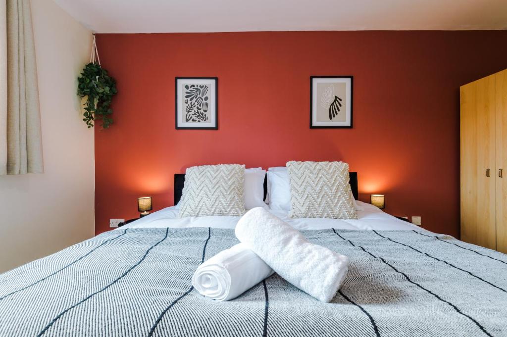 1 dormitorio con 1 cama grande y pared de color naranja en Central Mcr apt near AO arena, parking available nearby en Mánchester