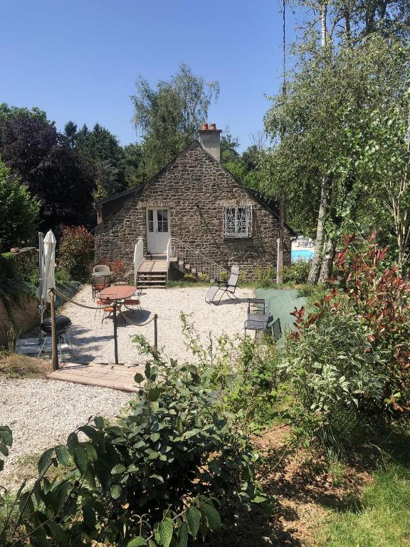 une maison en pierre avec une table et des chaises dans une cour dans l'établissement Le Mariotte, à Pont-et-Massène