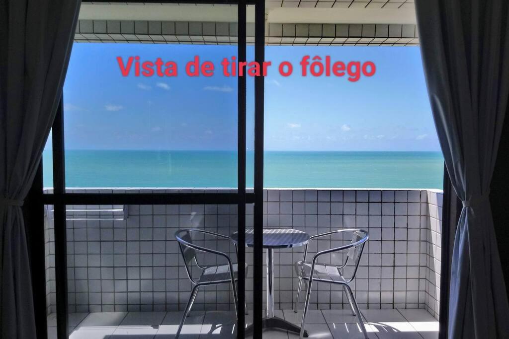 a table and two chairs in front of a window at Conforto e melhor vista - 100 metros da praia in Natal