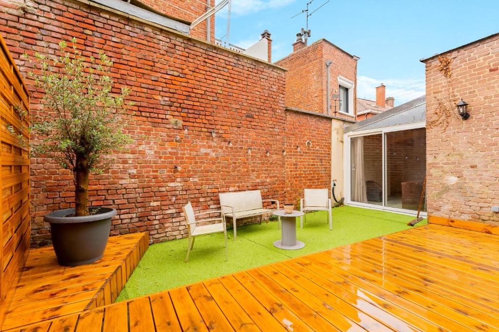 un patio con tavolo, sedie e muro di mattoni di La Perle de Lens - Belle maison avec grande terrasse a Lens