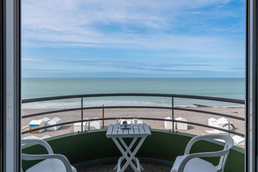 een tafel en stoelen op een balkon met uitzicht op het strand bij Le Trimaran 40 in Mers-les-Bains
