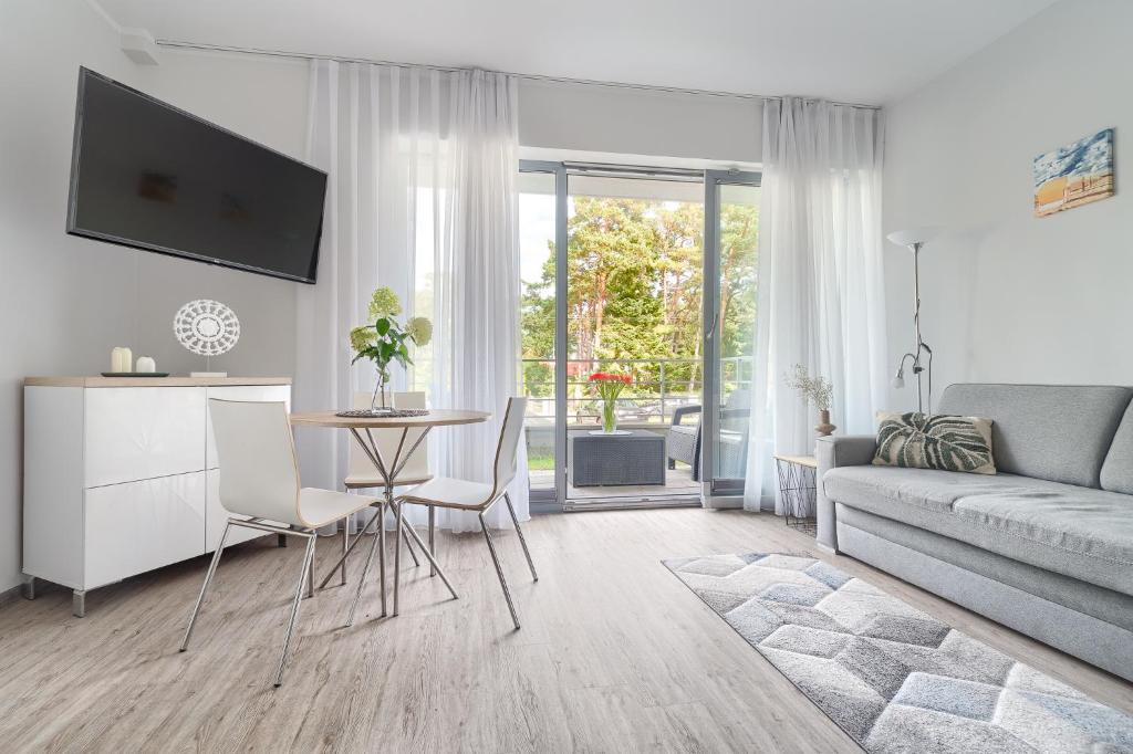 a living room with a couch and a table and chairs at Apartament Doris 3- Studio z wanną in Pobierowo