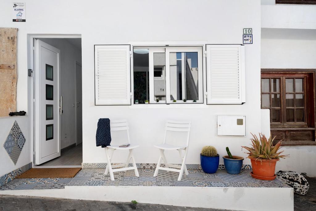 duas cadeiras brancas sentadas num pátio em frente a uma casa em Casa Marion em El Golfo