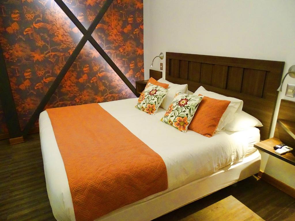 a bedroom with a bed with an orange blanket and pillows at BHB Hotel Boutique in Santiago