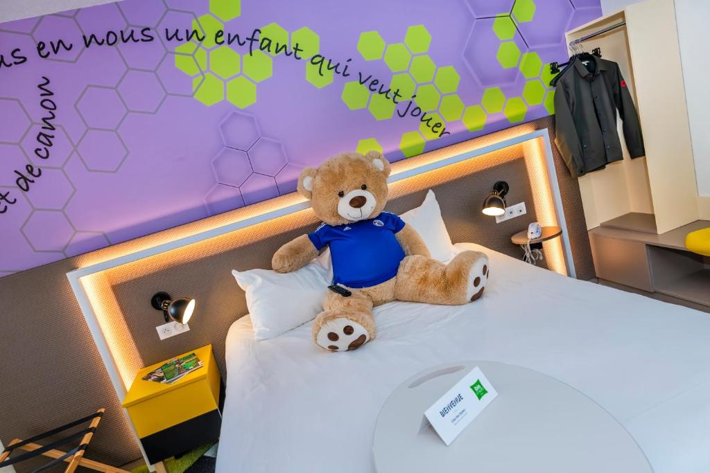 un ours en peluche assis au-dessus d'un lit dans l'établissement ibis Styles Strasbourg Stade de la Meinau, à Strasbourg