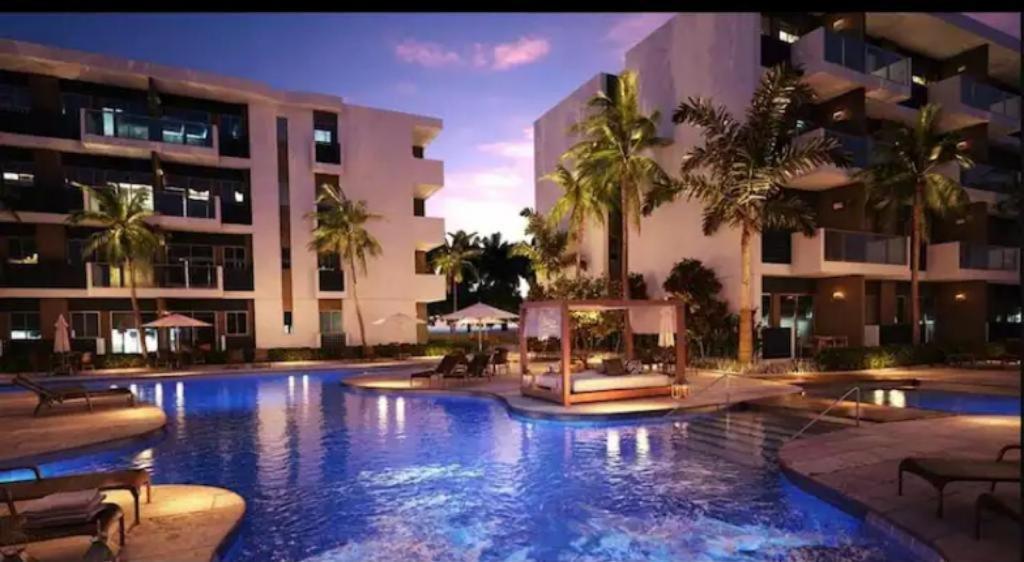 uma grande piscina num hotel com palmeiras em Makia Flat Muro Alto em Porto de Galinhas