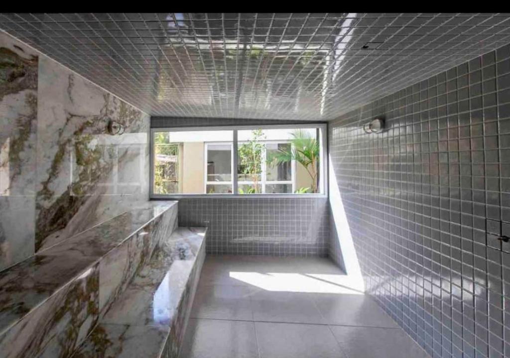 baño con ventana y pared de azulejos en JARDIM DAS PALMEIRAS II - HOME RESORT, en Ubatuba