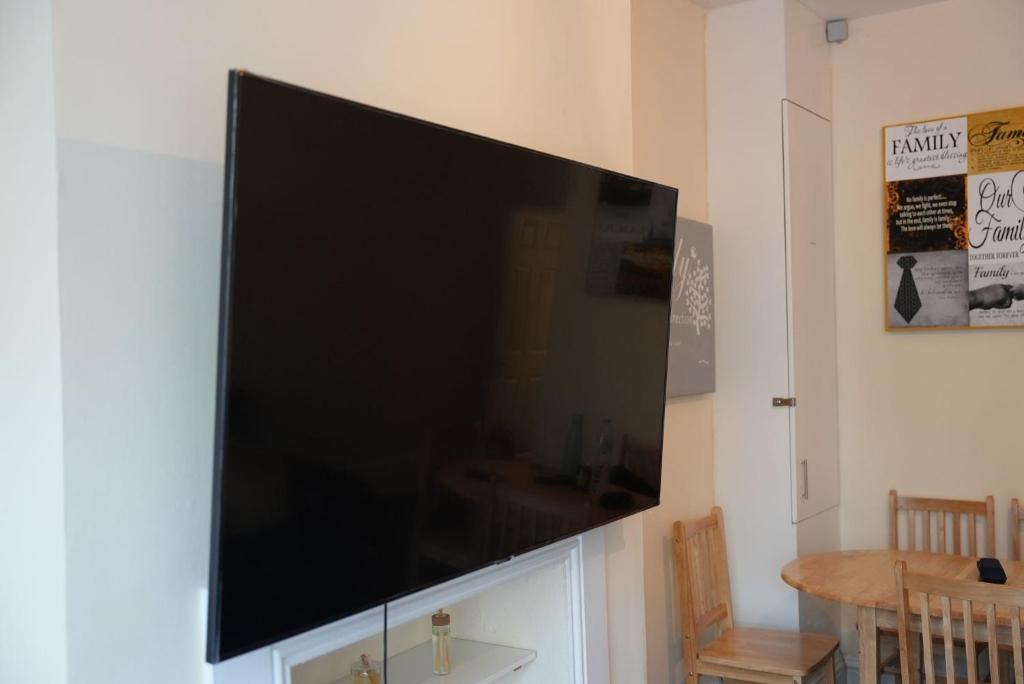 une grande télévision à écran plat accrochée au mur. dans l'établissement Spacious 5-Bed Retreat, à Londres