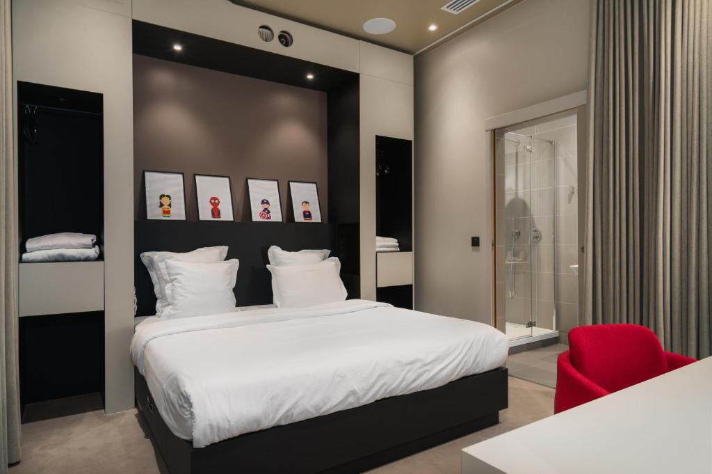 a bedroom with a large bed and a red chair at Maison Nô - Hôtel et Rooftop in Lyon
