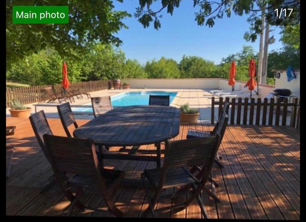 una terraza de madera con mesa y sillas junto a una piscina en La Maison Tourouzelle, en Lauraguel