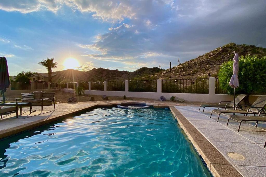 a swimming pool with chairs and the sun in the background at Desert Canyon Retreat W Heated Pool & Desert View in Phoenix