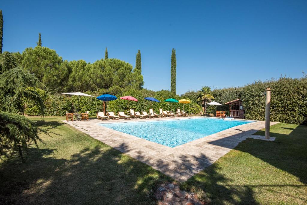 a swimming pool with umbrellas and chairs at Appartamento il Pino in Rapolano Terme