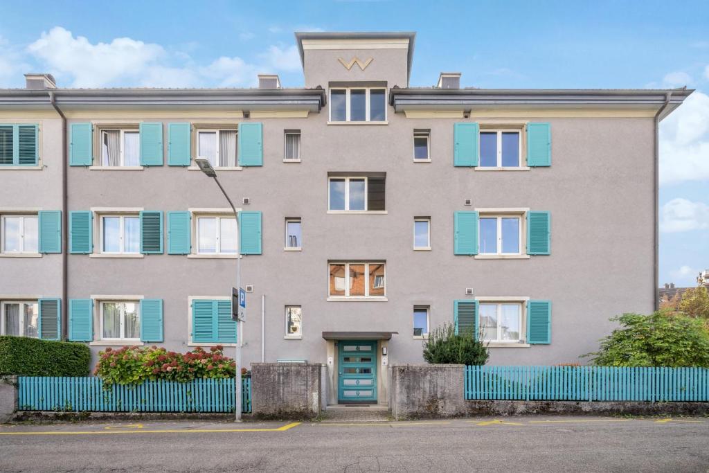 um edifício de apartamentos com persianas azuis e uma cerca azul em Dohlenweg 2 em Zürich