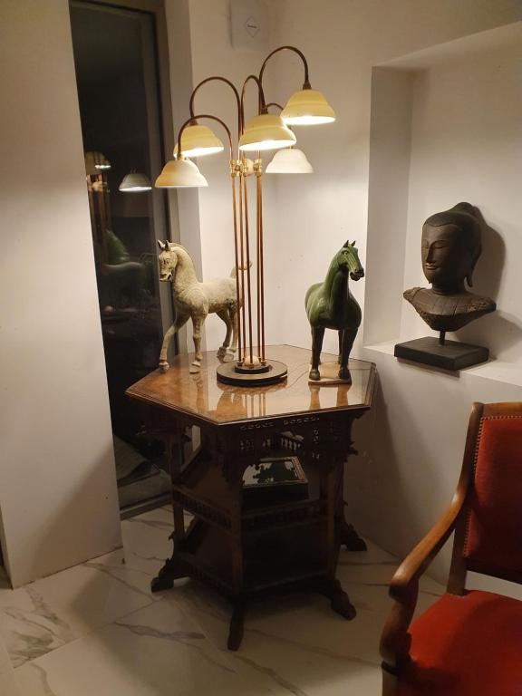 a table with a lamp and some statues on it at Villa Blanche in Arles