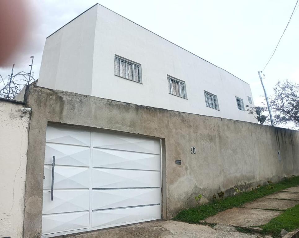 - un bâtiment blanc avec une grande porte de garage dans l'établissement Recanto Trevo da Pampulha, à Belo Horizonte