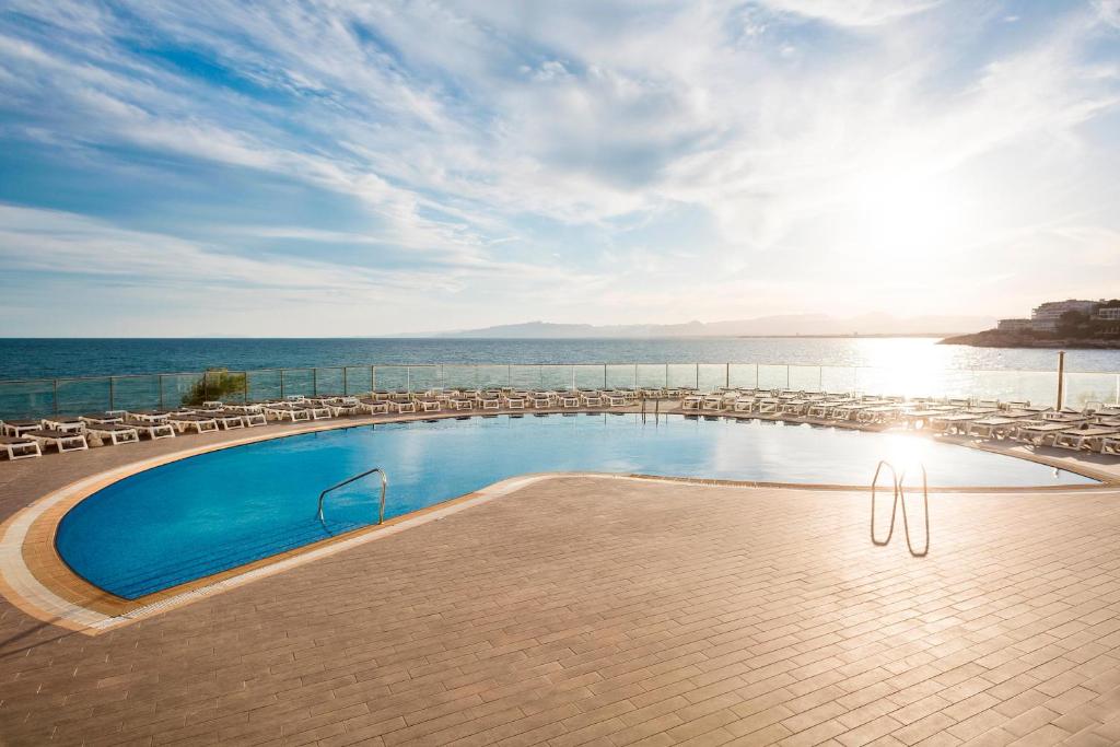 a swimming pool with chairs and the ocean in the background at Hotel Best Negresco in Salou