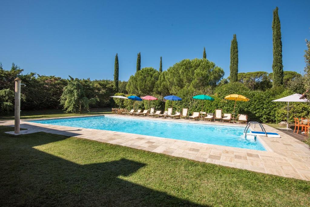 una piscina con sillas y sombrillas en un patio en Appartamento la Torretta en Rapolano Terme