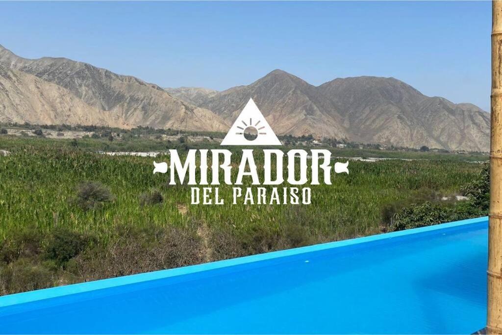 una señal para un hotel con montañas en el fondo en Mirador del Paraiso, en Lunahuaná