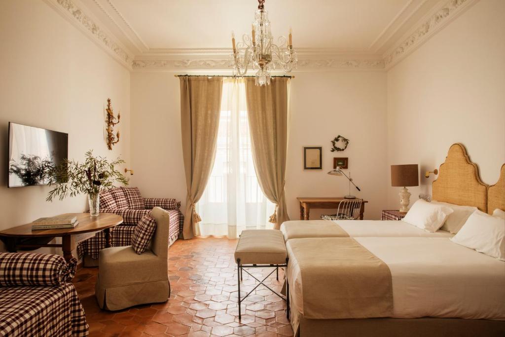 カセレスにあるCasa Pizarro Hotelのベッド2台とシャンデリアが備わるホテルルームです。