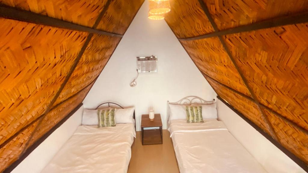 Duas camas num quarto com tectos em madeira em Casa Cabana Mabalacat em Mabalacat