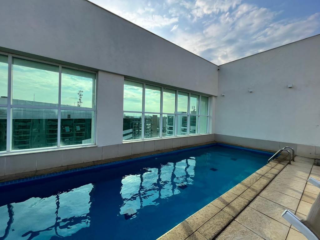 a swimming pool in the middle of a building with windows at Quarto de Luxo - Saint Moritz in Brasília