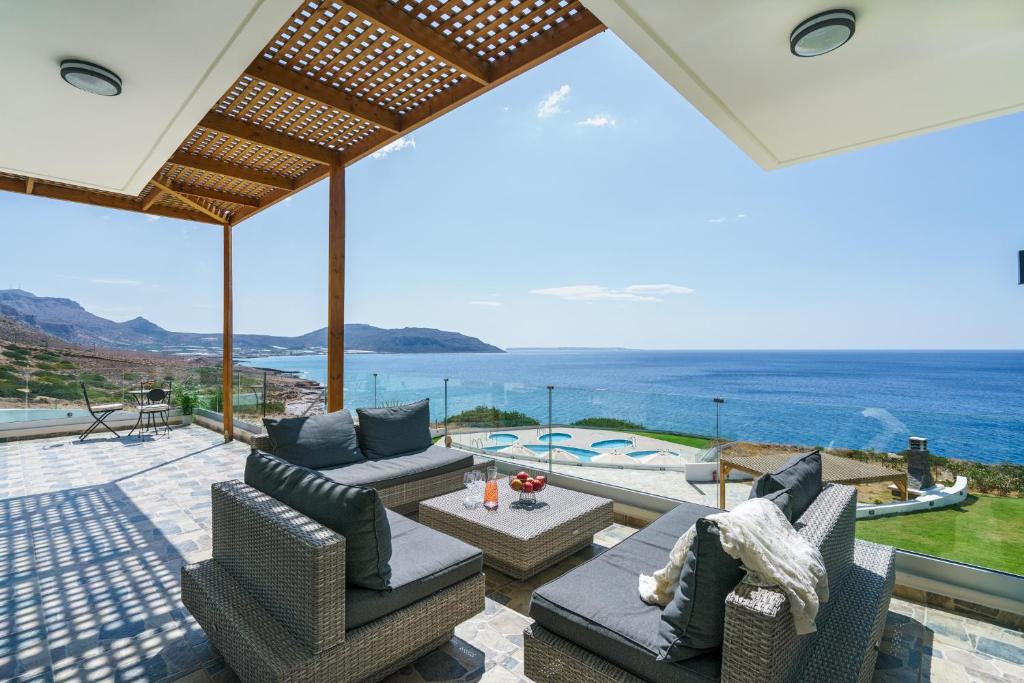 een patio met uitzicht op de oceaan bij Beachfront Villa Atalandia with Heated Pool, Gym, BBQ & Office in Goúdhouros