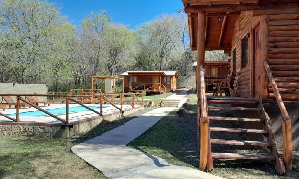 a log cabin with a swimming pool next to a house at Cabañas Samay in Casa Grande