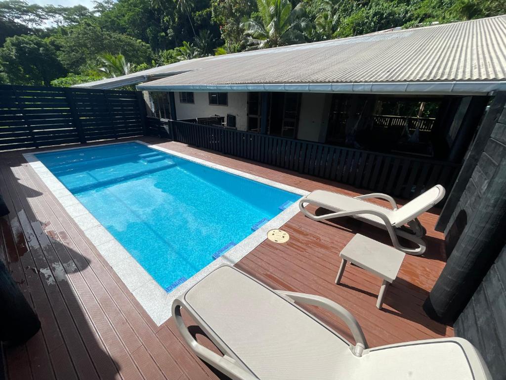 ein Pool auf einer Terrasse mit zwei Liegestühlen daneben in der Unterkunft Villa Honey Rose - Rarotonga in Arorangi
