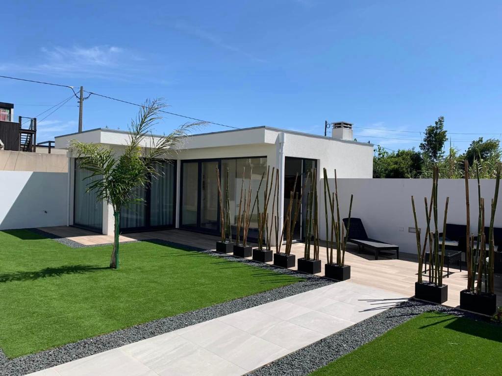 une maison avec une cour plantée d'herbes et de palmiers dans l'établissement Oliver Beach House, à Poço da Cruz