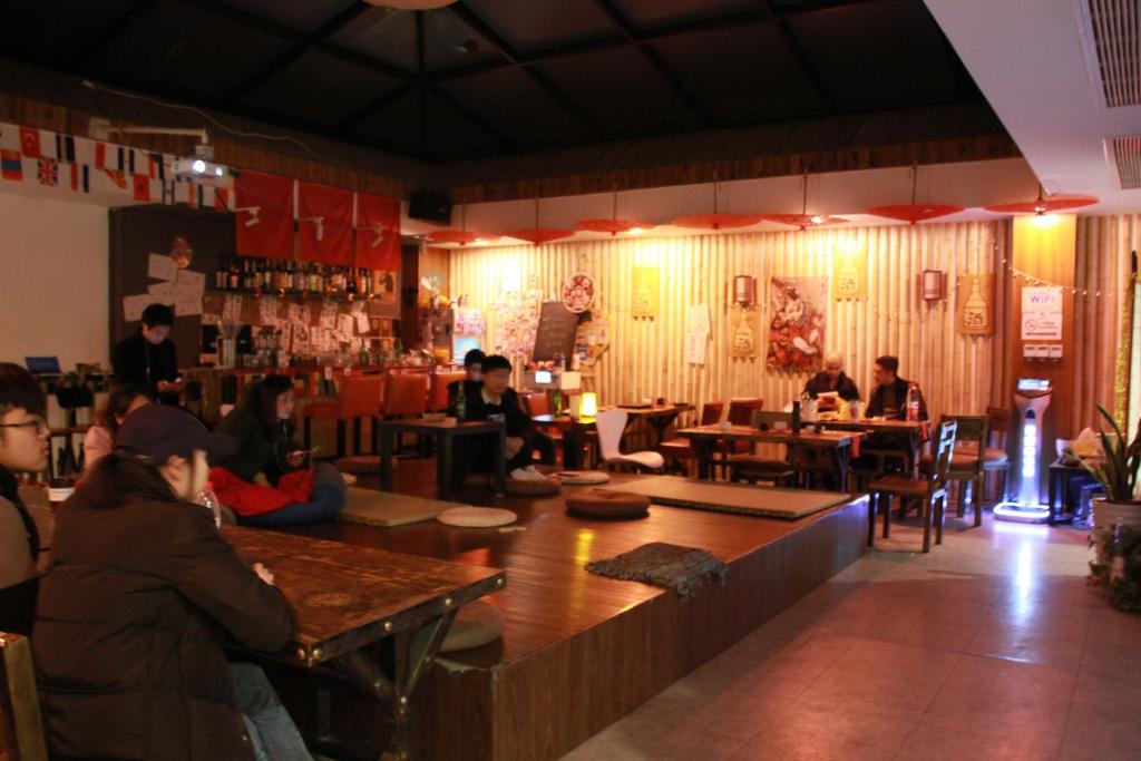 un grupo de personas sentadas en mesas en un restaurante en Onederz Hostel Hangzhou en Hangzhou