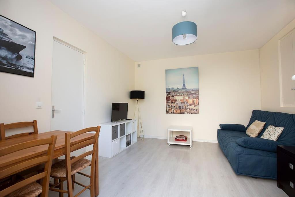 ein Wohnzimmer mit einem blauen Sofa und einem Tisch in der Unterkunft Le Bon Repos - Séjours professionnels et vacances en famille aux portes de Paris in Garches